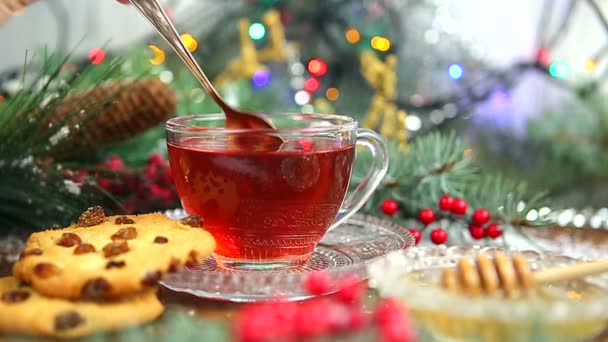 冬茶一杯茶, 蜂蜜和羊角面包或饼干, 在雪中的一棵圣诞树的树枝, 圣诞灯 — 图库视频影像