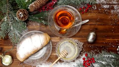 Kış çay A fincan çay bal ve kruvasan veya çerezleri, kar, Noel ışıkları bir Noel ağacındaki bir dalı ile