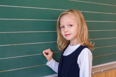 İlk sınıf öğrencisi bir kız okul ders yeşil tahtaya yazma