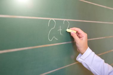 İlk sınıf öğrencisi bir kız okul ders yeşil tahtaya yazma