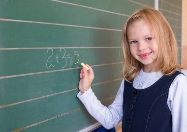 İlk sınıf öğrencisi bir kız okul ders yeşil tahtaya yazma