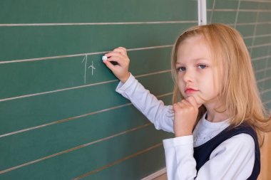 İlk sınıf öğrencisi bir kız okul ders yeşil tahtaya yazma