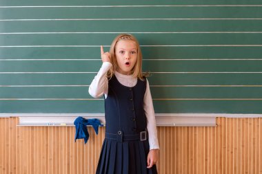 İlk sınıf öğrencisi bir kız okul ders yeşil tahtaya yazma