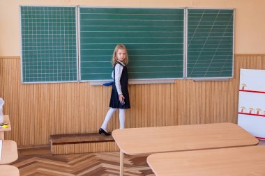 İlk sınıf öğrencisi bir kız okul ders yeşil tahtaya yazma