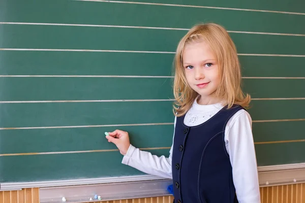 İlk sınıf öğrencisi bir kız okul ders yeşil tahtaya yazma — Stok fotoğraf