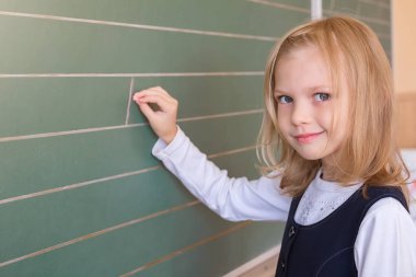 İlk sınıf öğrencisi bir kız okul ders yeşil tahtaya yazma