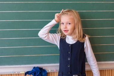 İlk sınıf öğrencisi bir kız okul ders yeşil tahtaya yazma