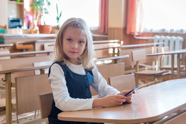 Ein erstklassiger Schüler in der Schule spielt das Spiel am Telefon. Emotionen der Schüler — Stockfoto