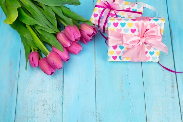 Hediye kutusu ile mavi ahşap tabloda Lale buketi. Mutlu kadın gün. 8 Mart, anneler günü. Yat ve uzay kopyalayın