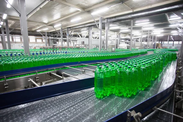 Green plastic bottles on the conveyor belt at the plant