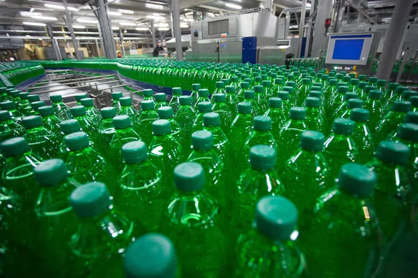 Green plastic bottles on the conveyor belt at the plant