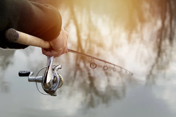Pesca en el río.Un pescador con una caña de pescar en la orilla del río. Hombre pescador captura un pez — Foto de Stock
