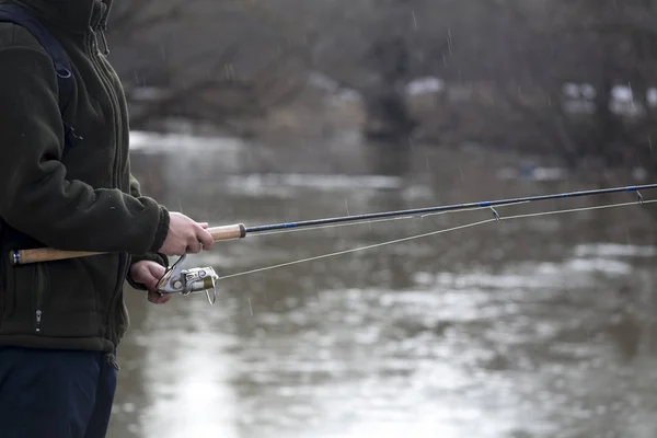 Pesca en el río.Un pescador con una caña de pescar en la orilla del río. Hombre pescador captura un pez — Foto de Stock