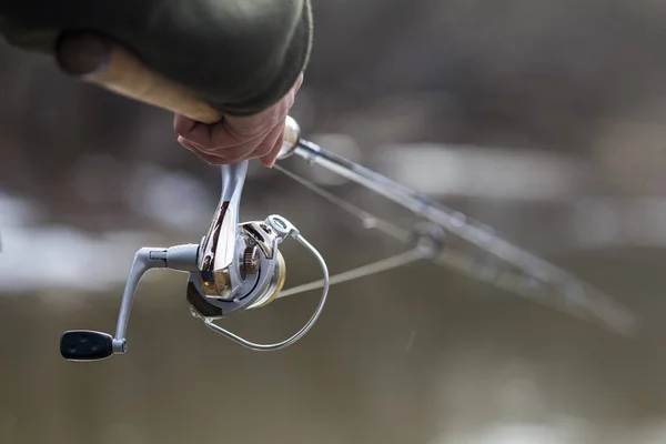 Pesca en el río.Un pescador con una caña de pescar en la orilla del río. Hombre pescador captura un pez — Foto de Stock