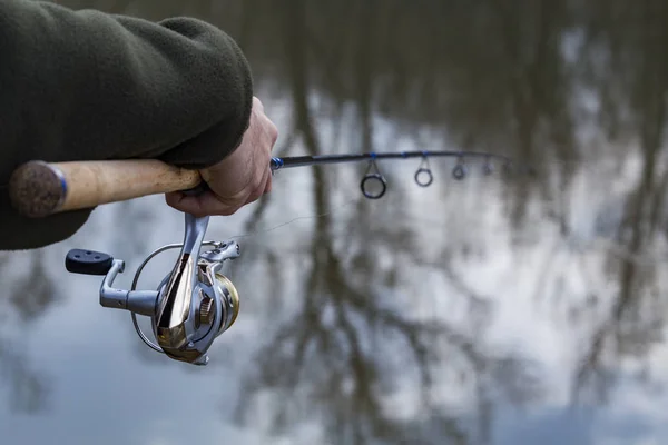 Pesca en el río.Un pescador con una caña de pescar en la orilla del río. Hombre pescador captura un pez — Foto de Stock