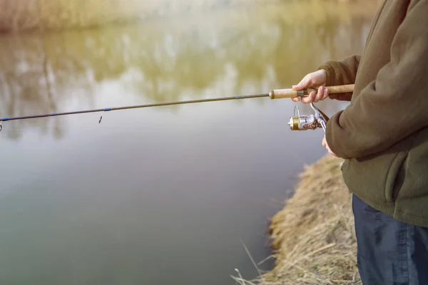 Pesca en el río.Un pescador con una caña de pescar en la orilla del río. Hombre pescador captura un pez — Foto de Stock