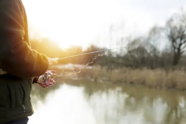 Pesca en el río.Un pescador con una caña de pescar en la orilla del río. Hombre pescador captura un pez — Foto de Stock
