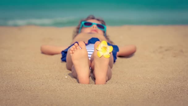 Niño en la playa con flor en los dedos de los pies — Vídeo de stock