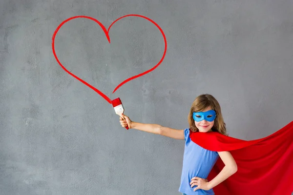 Superhéroe chica pintura corazón en la pared —  Fotos de Stock