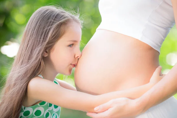 Ребенок целует живот беременной женщины — стоковое фото