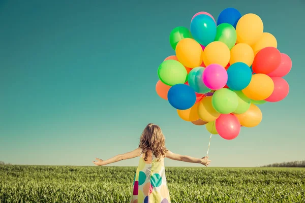 Criança com balões de brinquedo no campo de primavera — Fotografia de Stock