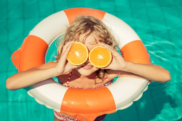 Girl with orange slices in swimming pool — Stock Photo, Image