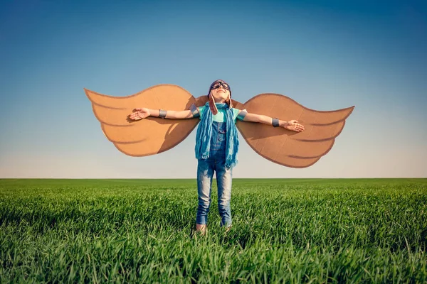 Счастливый ребенок играет с игрушечными крыльями бумаги — стоковое фото