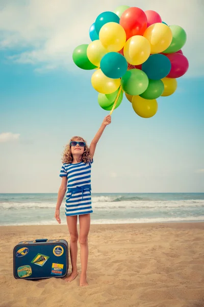 Счастливый ребенок играет на открытом воздухе против моря и неба — стоковое фото