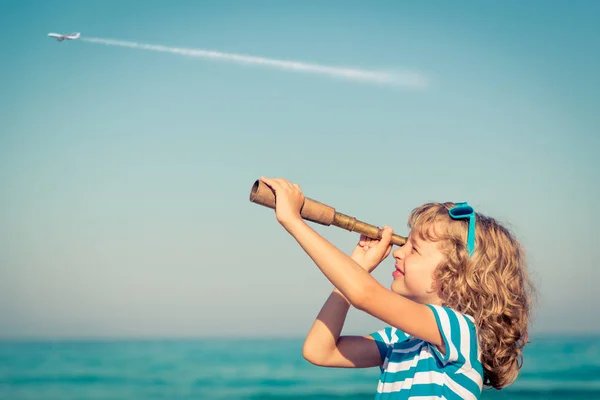 Glückliches Kind spielt draußen gegen Meer und Himmel — Stockfoto