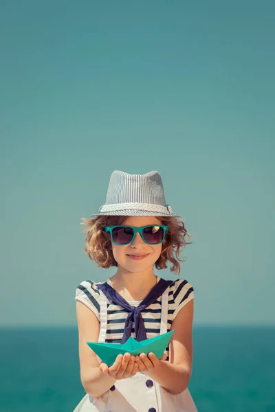 Ребенок с бумажным парусником на летних каникулах — стоковое фото