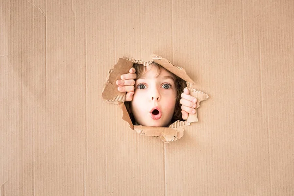 Child looking through hole of cardboard — Stock Photo, Image