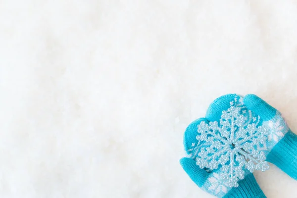 Mãos em mitenes segurando floco de neve decorativo — Fotografia de Stock