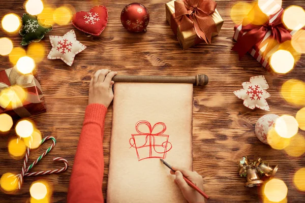 Hände zeichnen Geschenk auf Weihnachtsrolle — Stockfoto