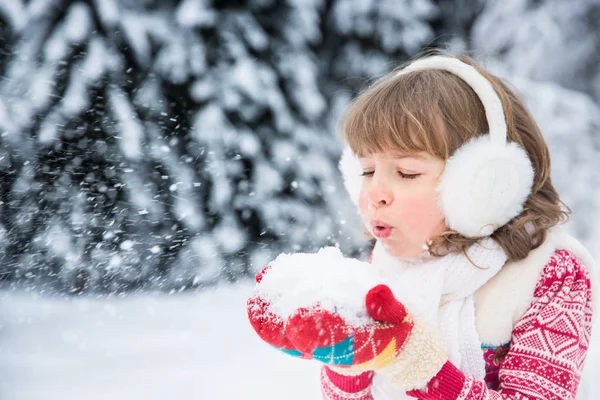 Mädchen bläst auf eine Handvoll Schnee — Stockfoto