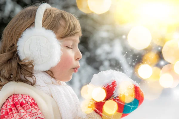 Mädchen bläst auf eine Handvoll Schnee — Stockfoto