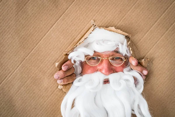 Kerstman op zoek door gat op karton — Stockfoto