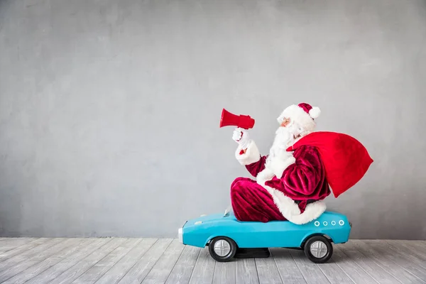 Santa Claus paardrijden speelgoedauto — Stockfoto