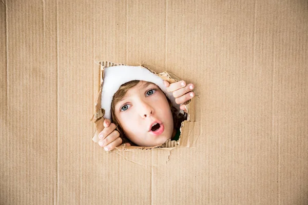 Chico divertido mirando a través del agujero en cartón — Foto de Stock