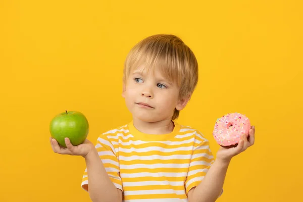 Criança feliz segurando donut e maçã — Fotografia de Stock