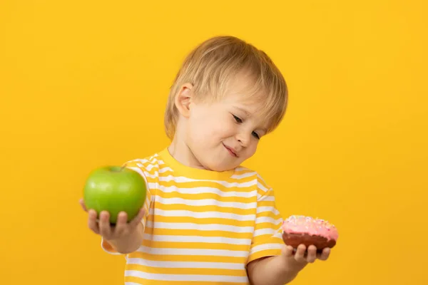 Ευτυχισμένο παιδί που κρατάει ντόνατ και μήλο — Φωτογραφία Αρχείου