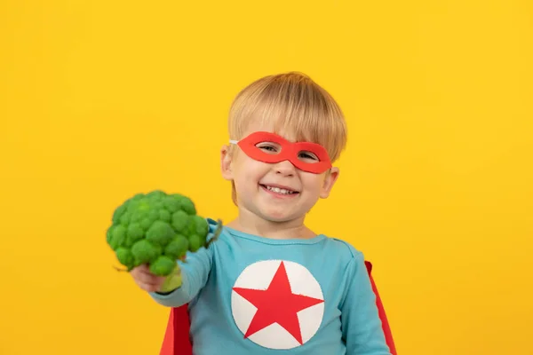 Superheldenkind hält Brokkoli in der Hand — Stockfoto