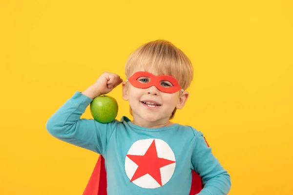 Superhrdina dítě drží jablko — Stock fotografie