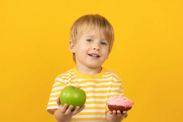 Lyckligt barn som håller munk och äpple — Stockfoto