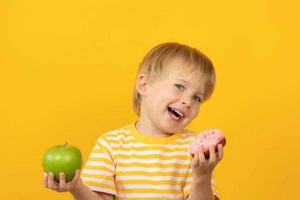Ευτυχισμένο παιδί που κρατάει ντόνατ και μήλο — Φωτογραφία Αρχείου