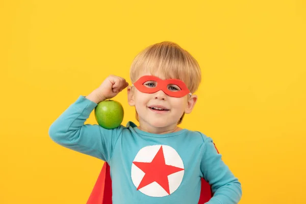 Criança super-herói segurando maçã — Fotografia de Stock