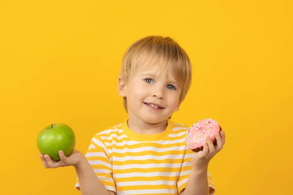 Criança feliz segurando donut e maçã — Fotografia de Stock