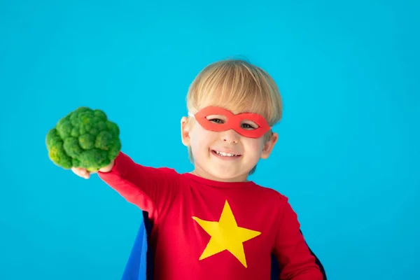 Superheldenkind hält Brokkoli in der Hand — Stockfoto