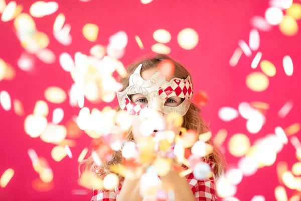 Menina fantasia soprando confete contra o chão de padaria rosa — Fotografia de Stock