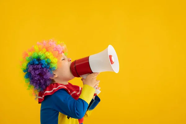Vtipné dítě klaun hrát proti žluté pozadí — Stock fotografie