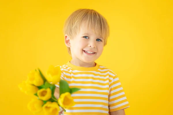 Criança feliz segurando buquê de primavera de flores — Fotografia de Stock